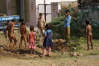 Indische Kinder spielen mit einem selbst gebastelten Springbrunnen aus einem Wasserrohr.