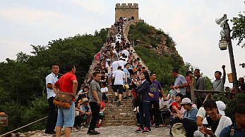 Auf der Mauer, auf der Lauer steht eine Touristin – und daneben natürlich die obligatorische Überwachungskamera.