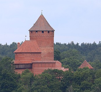 Von der Ferne aus betrachtet lugt die Burg Turaida pittoresk zwischen Bäumen hervor.